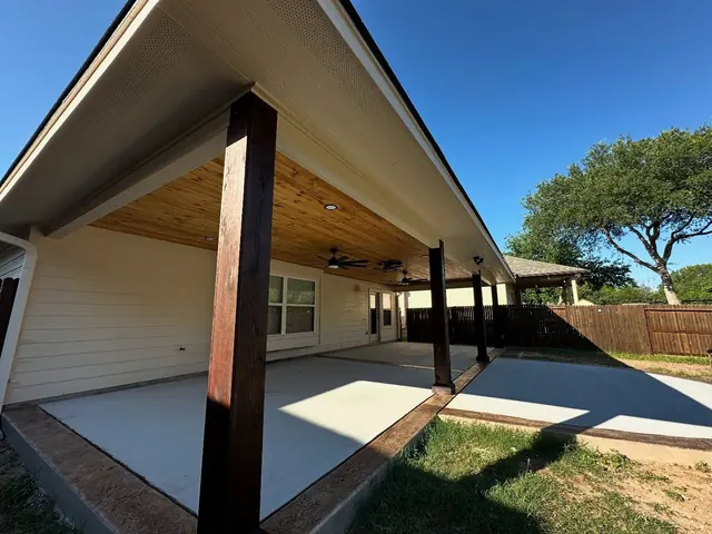 Patio cover with dark steel posts and wood ceiling over a stained concrete patio
