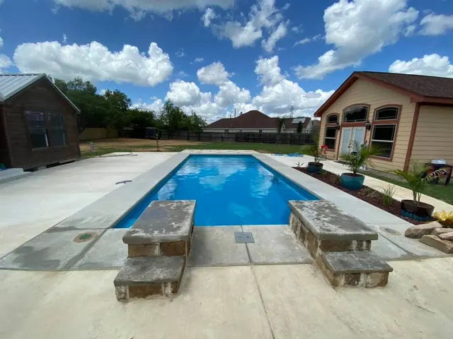 Pool deck with stone benches and a covered patio