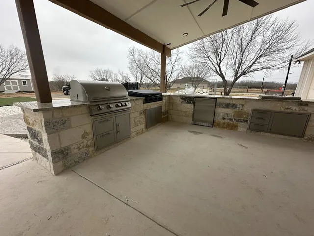Covered outdoor kitchen with stainless grill and stone base