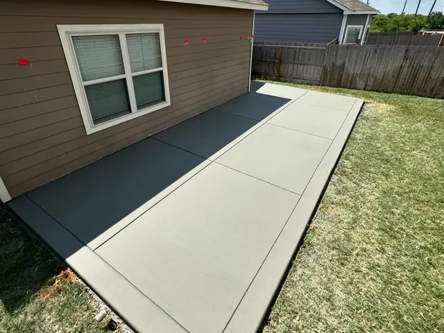 Broom-finish concrete slab with control joints along the side of a house