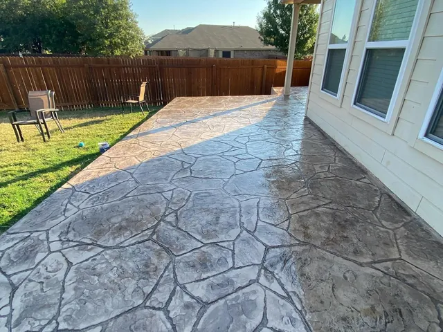 Gray stamped flagstone concrete patio along the side of a house