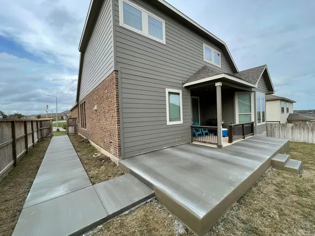 Concrete walkway leading to a back patio slab with steps